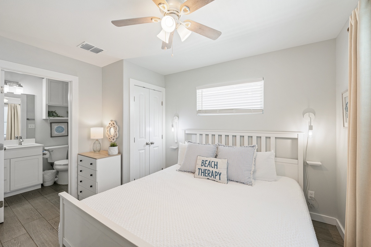 Slip into your serene coastal retreat, where crisp linens and gentle breezes from the ceiling fan promise restful nights. Your ensuite bathroom awaits just steps away for ultimate convenience.