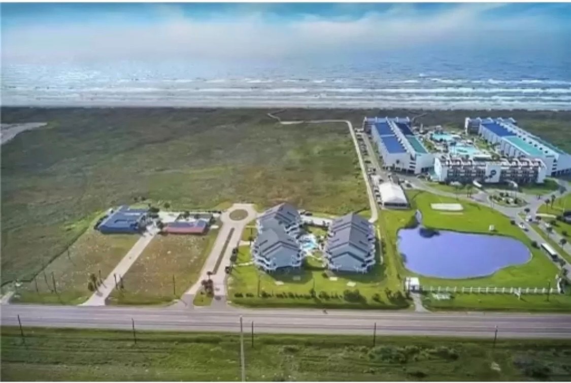 Oceanfront resort complex with swimming pools, green lawns, and direct beach access just steps from rolling waves.