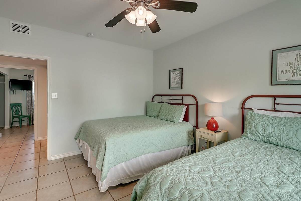Unwind in your peaceful twin bedroom with coastal-inspired decor and gentle ceiling fan keeping you cool.