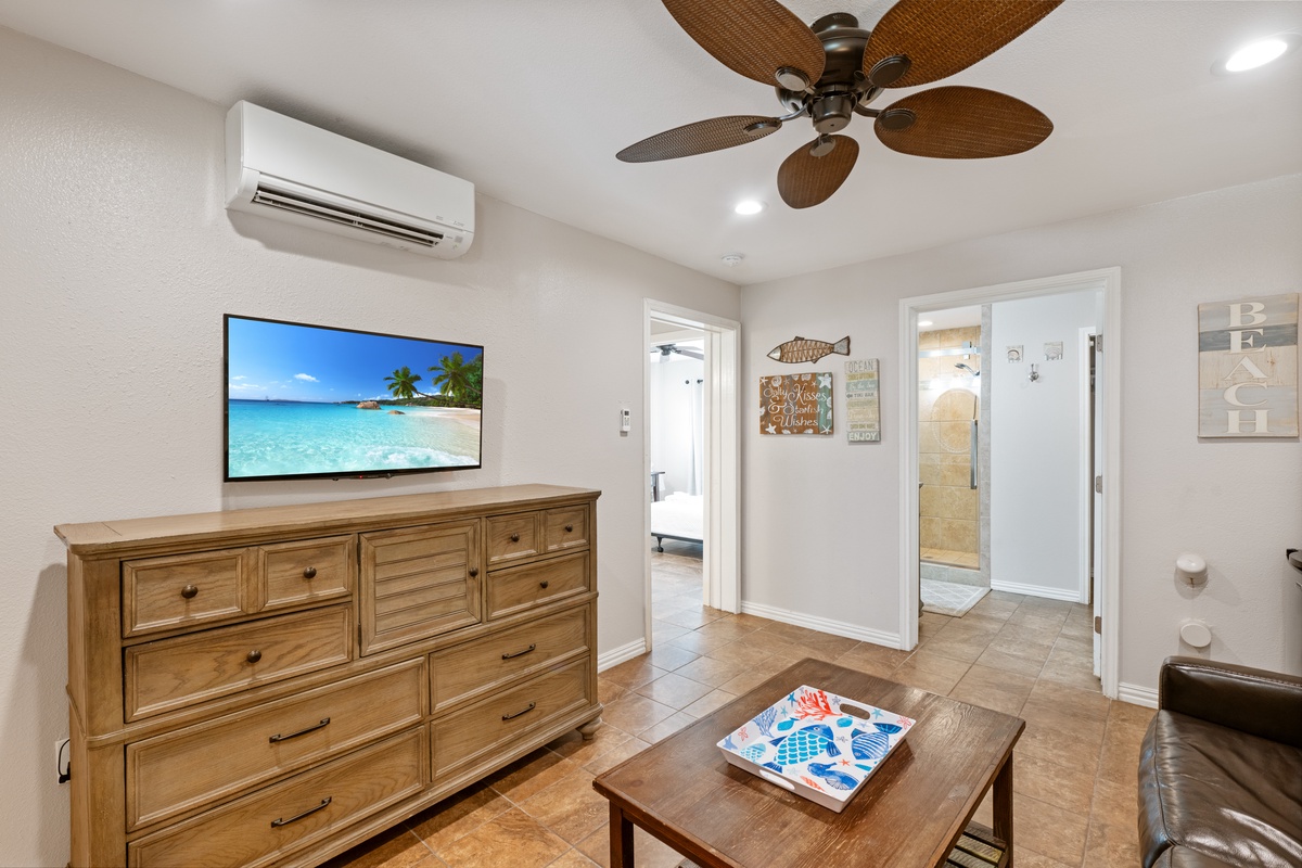 Relax in your comfortable living space with tropical vibes, featuring AC, ceiling fan, and entertainment for perfect vacation downtime.