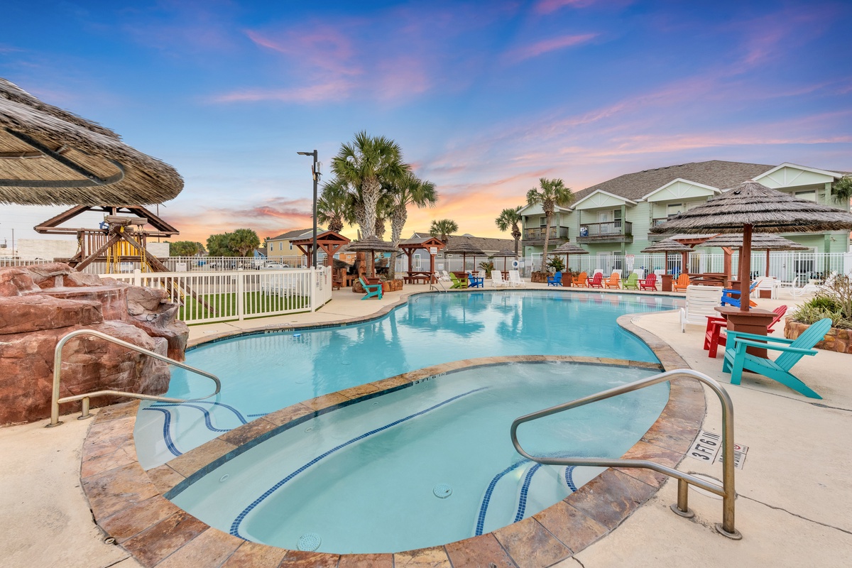 The resort's stunning pool complex offers multiple pools with rock features, tropical thatched umbrellas, and colorful seating under beautiful evening skies.