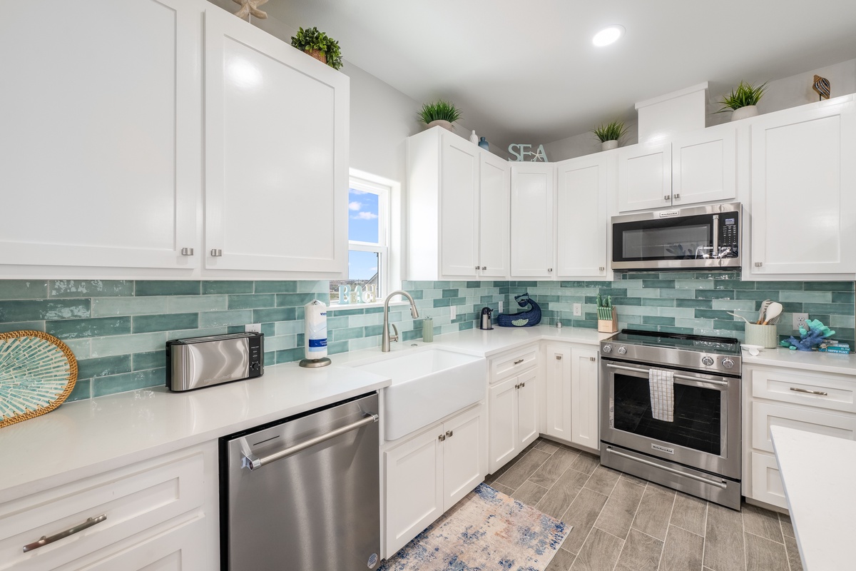 Your bright white kitchen features sea-inspired teal subway tiles and stainless steel appliances for effortless cooking during your stay.