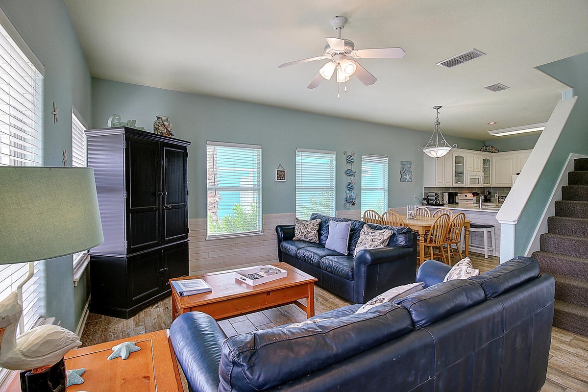 Relax in your spacious living area with comfortable leather seating, ceiling fan, and bright windows overlooking the surroundings.