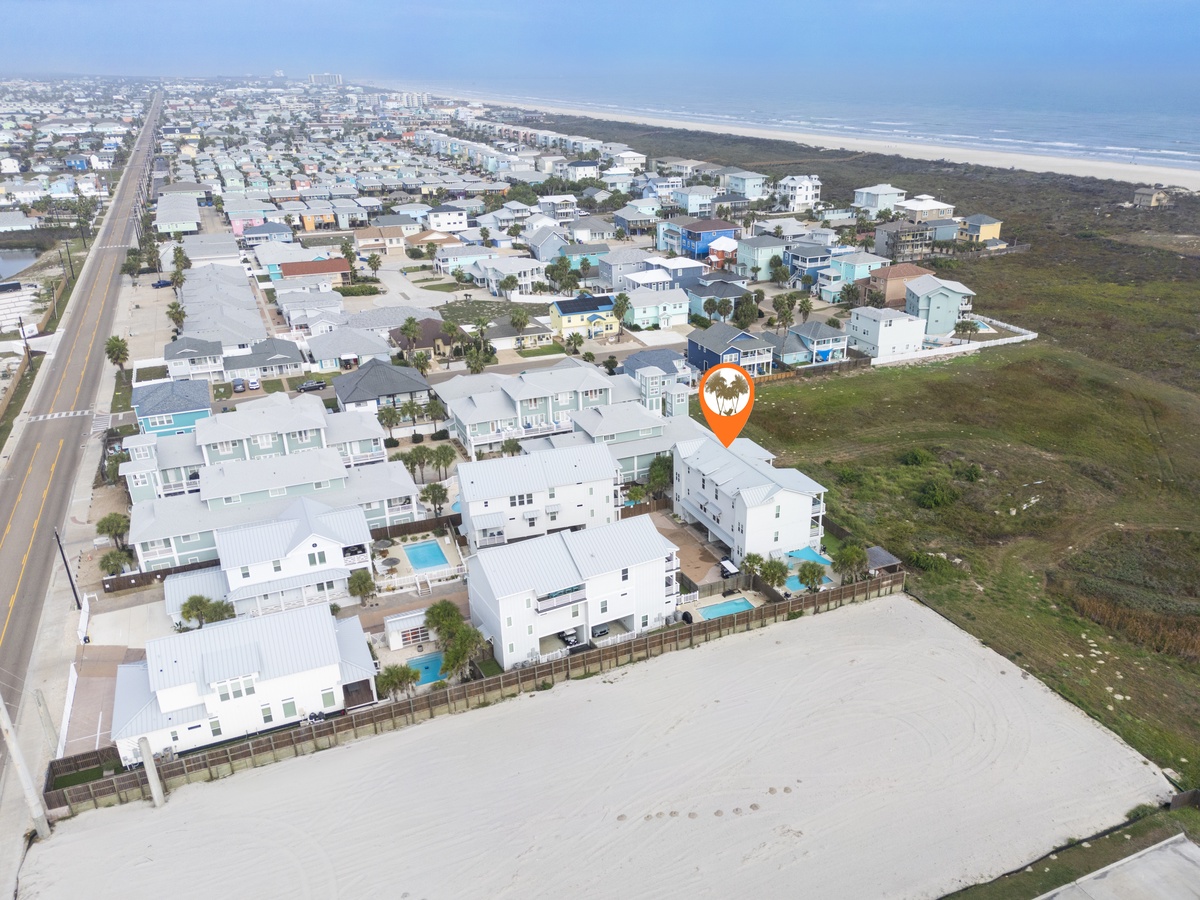 Aerial view of beachfront community featuring modern vacation homes with pools, just minutes from pristine coastline.