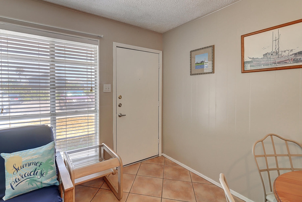 Step into your bright, welcoming entryway where coastal charm meets comfort. Natural light streams through blinds as nautical art sets the mood.