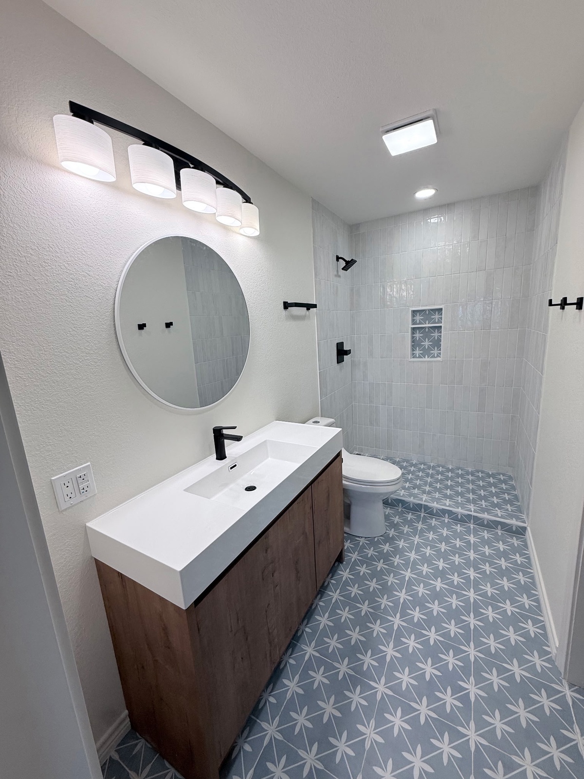 Your modern bathroom features a stylish vanity, walk-in shower, and eye-catching geometric tile flooring that brings contemporary charm to your daily routine.