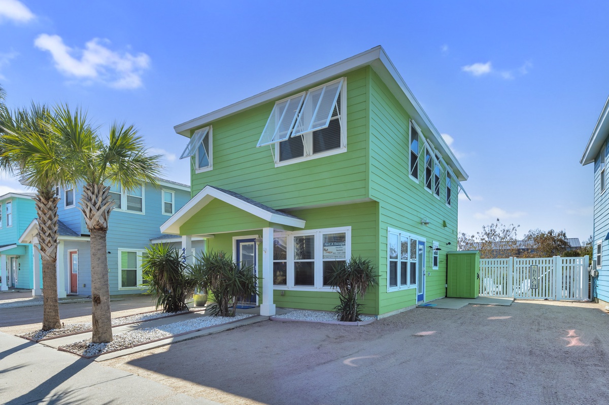 Vibrant green coastal cottage with palm trees and tropical charm in a sunny beachside neighborhood.