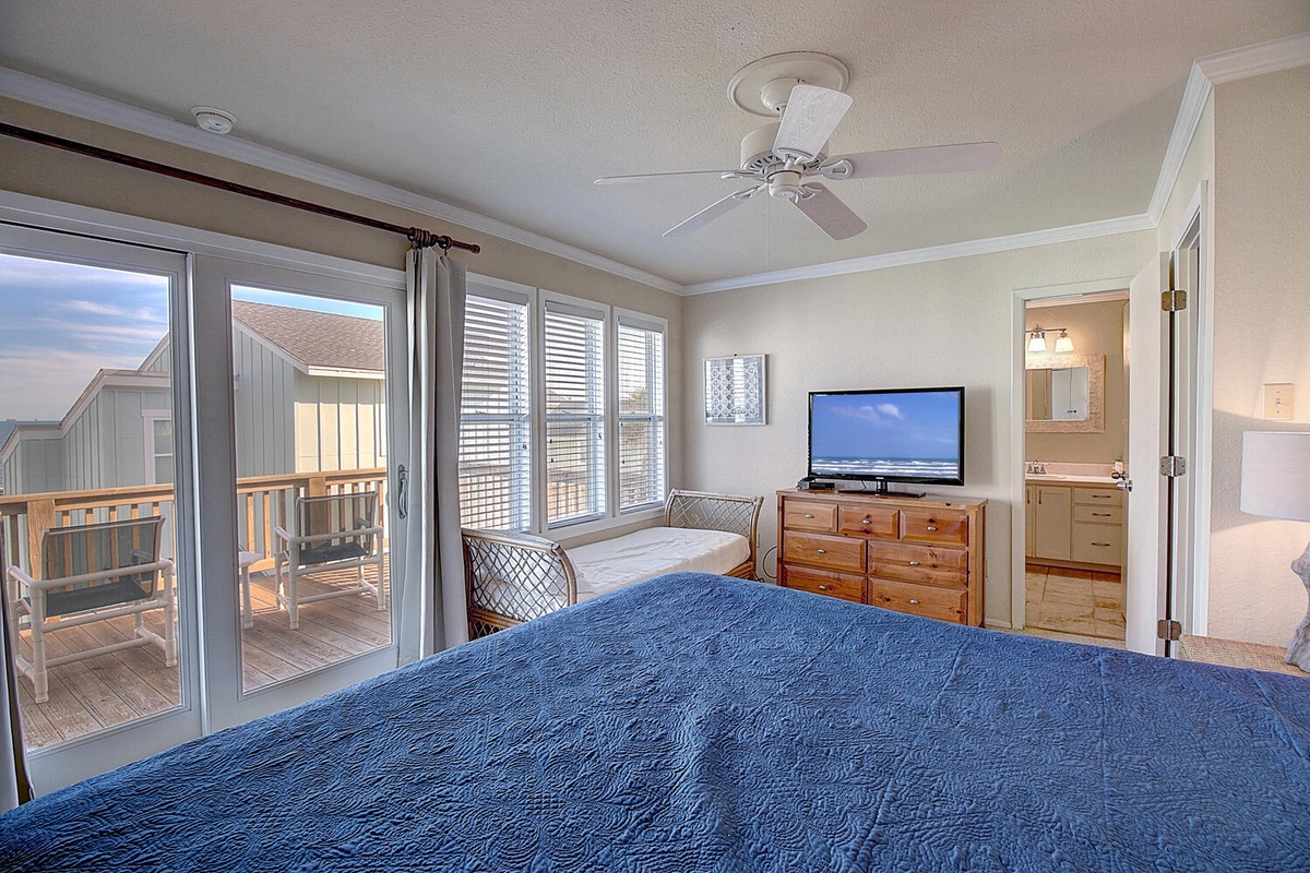 Your master bedroom offers coastal comfort with ocean blue bedding, private balcony access, and soothing ceiling fan breezes.