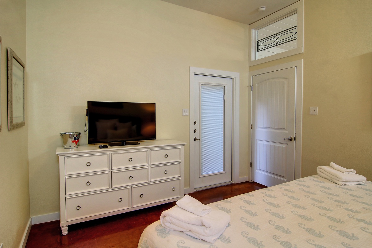 Your peaceful bedroom features a flat-screen TV, spacious dresser for storage, and fresh towels waiting for your arrival.