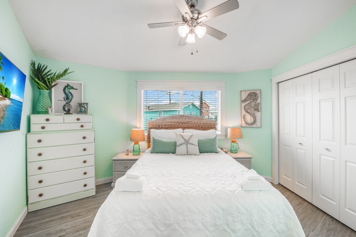 Drift off in this coastal-themed bedroom with soft mint walls, wicker headboard, and cheerful ocean décor that makes bedtime feel like a beach retreat.