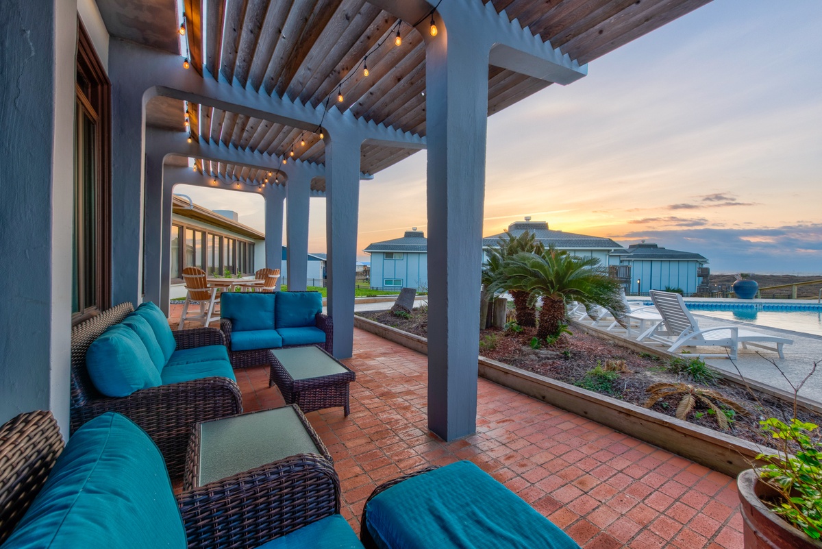 Unwind on your private covered terrace with plush seating, string lights, and stunning pool views as sunset paints the sky.