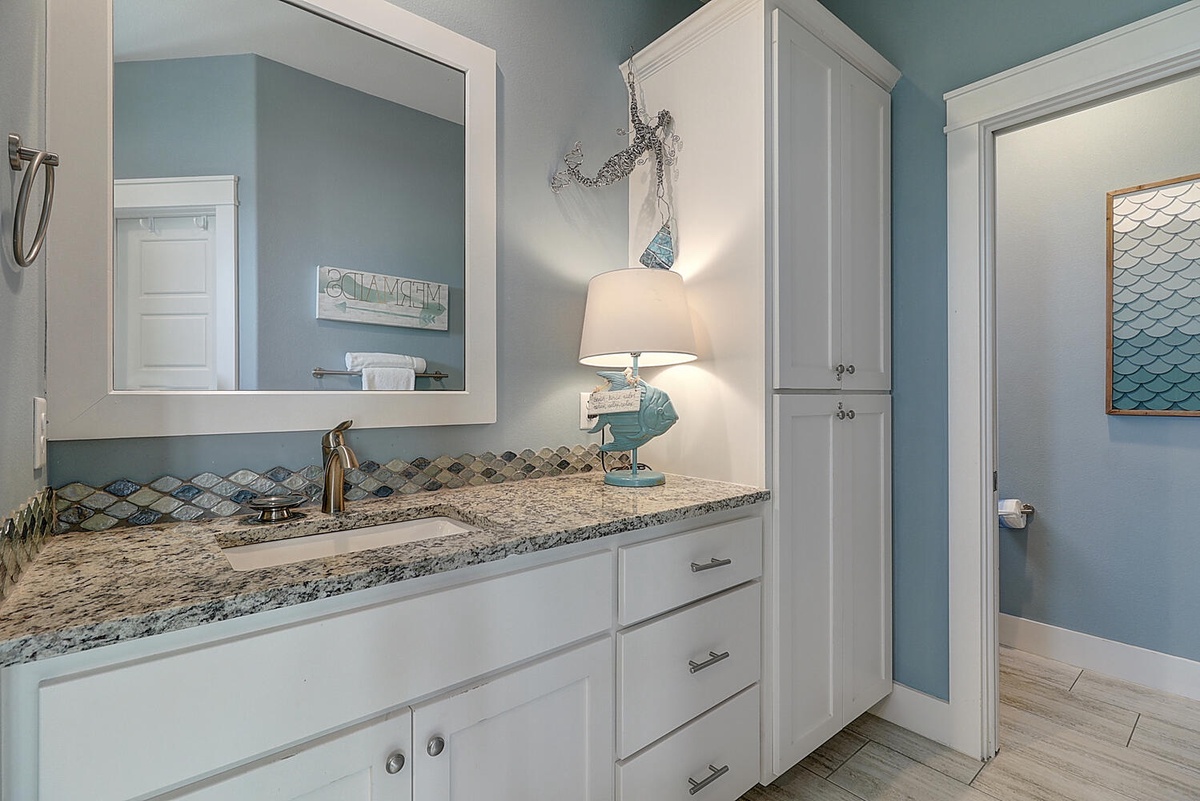 Your coastal-themed bathroom features marble countertops, custom cabinetry, and nautical touches that create a spa-like retreat.
