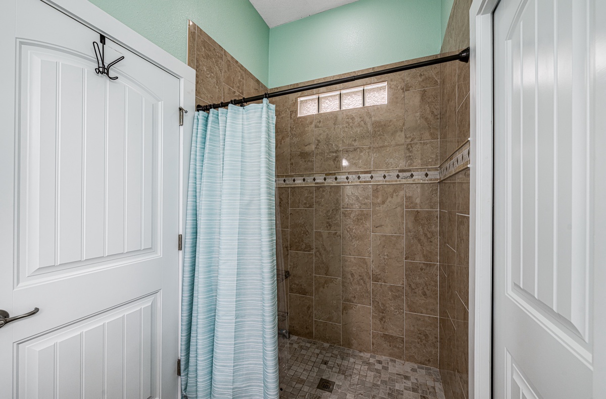 Step into your private spa-like shower with beautiful stone tile walls and refreshing mint accents that create a serene morning ritual.