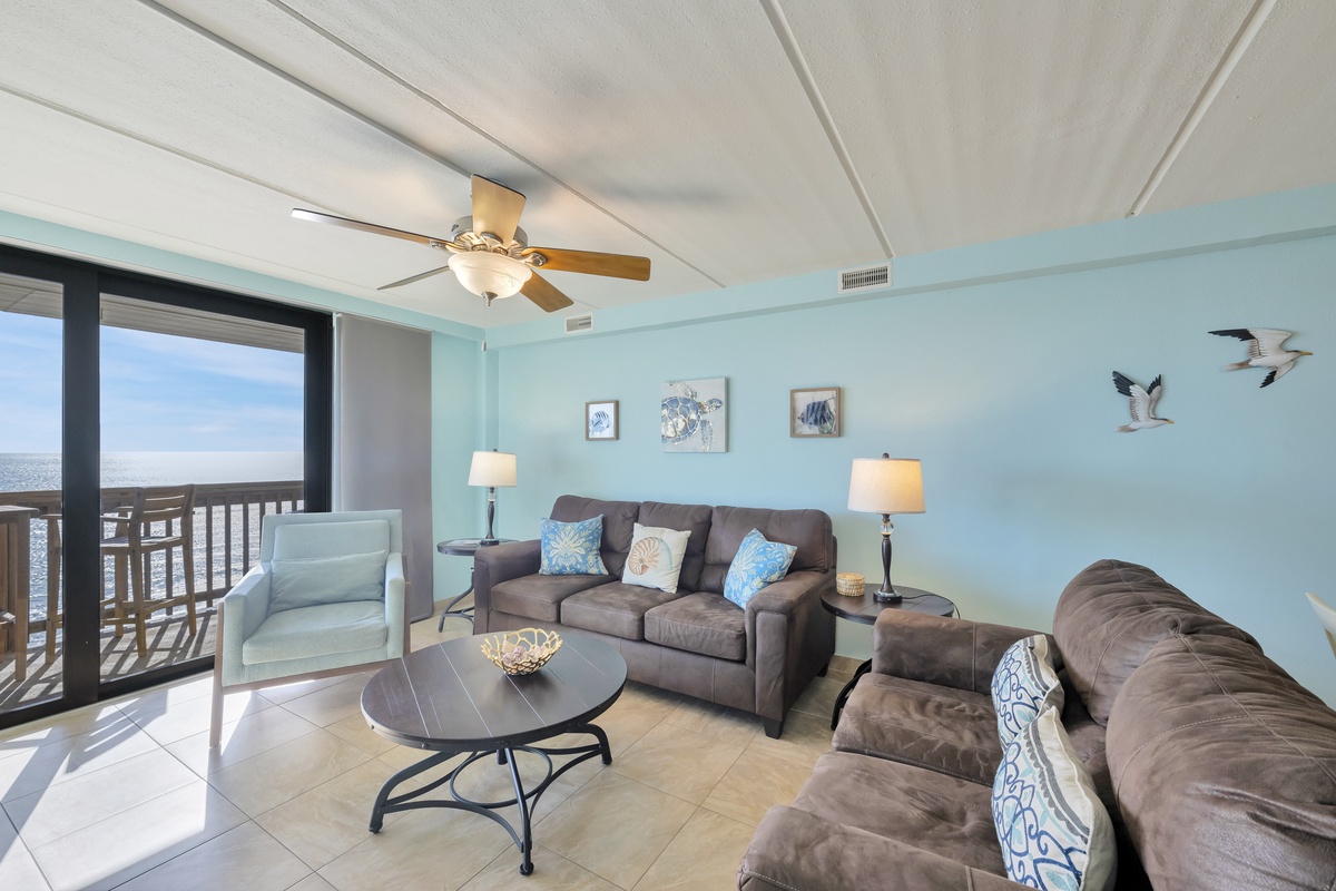 Unwind in your coastal living room with ocean views through floor-to-ceiling windows. Soft blue walls and comfortable seating create the perfect seaside retreat.
