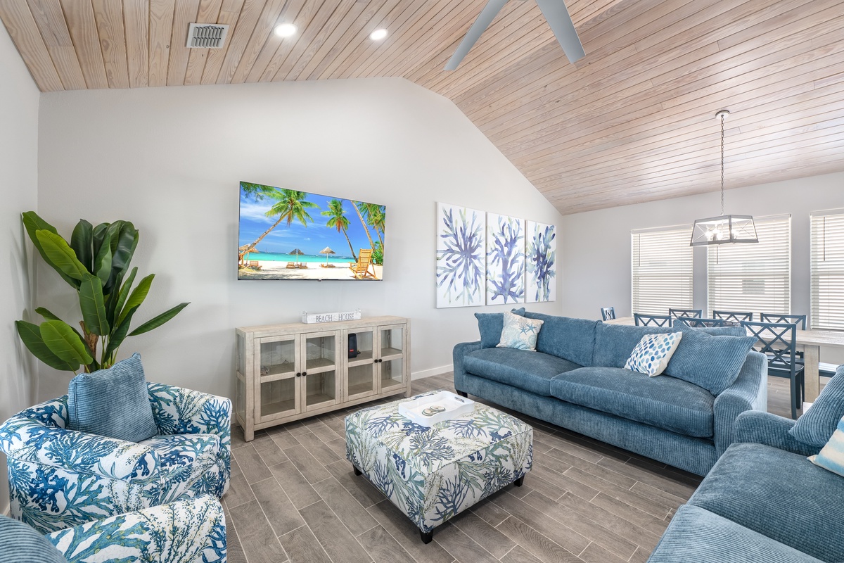 Unwind in this coastal-inspired living room where ocean blues meet warm wood, perfect for movie nights under the ceiling fan.