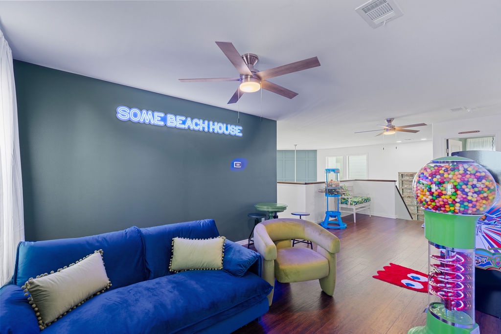 Unwind in your vibrant living space featuring plush blue seating and colorful neon lighting that creates a fun, beachy atmosphere.