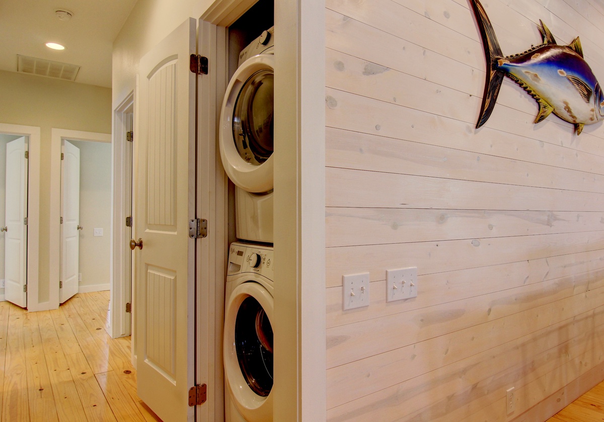 Your coastal retreat features convenient in-unit laundry tucked behind charming cabinet doors, with natural wood floors and nautical touches throughout.