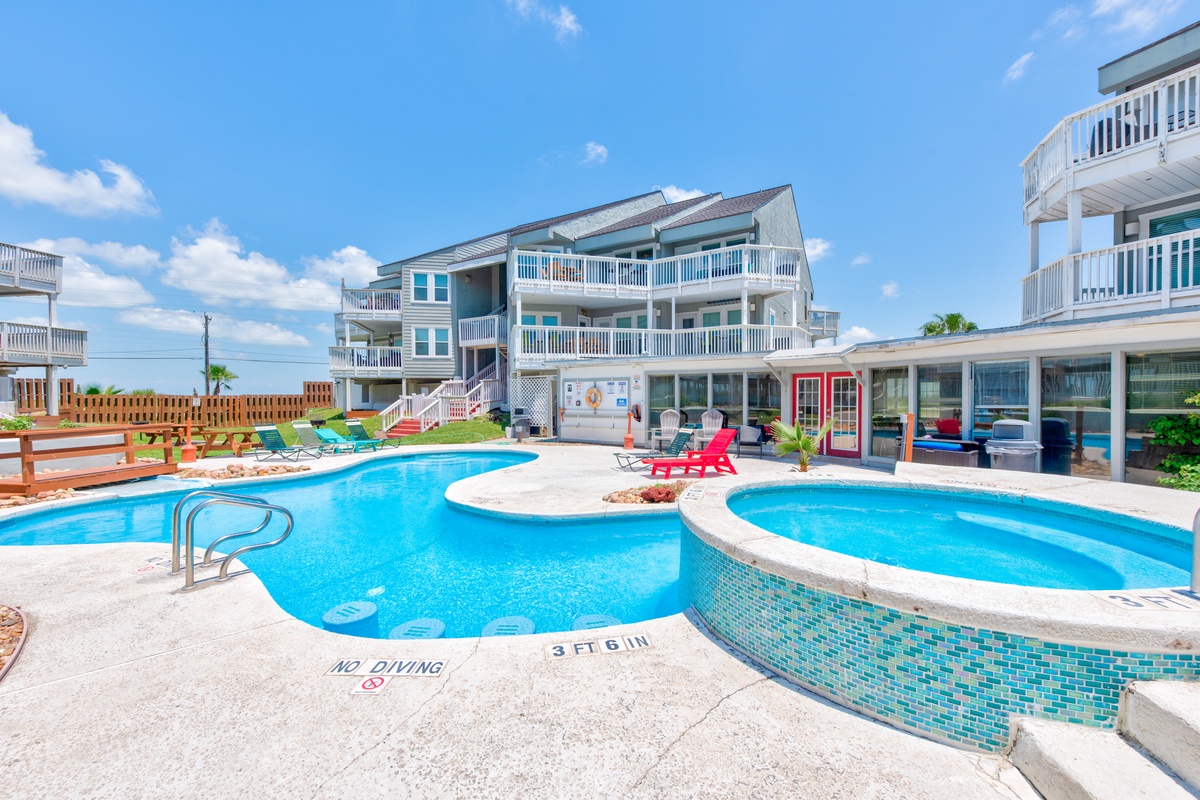Spacious beachside vacation rental complex featuring outdoor swimming pool, hot tub, and multi-level accommodations with balconies.