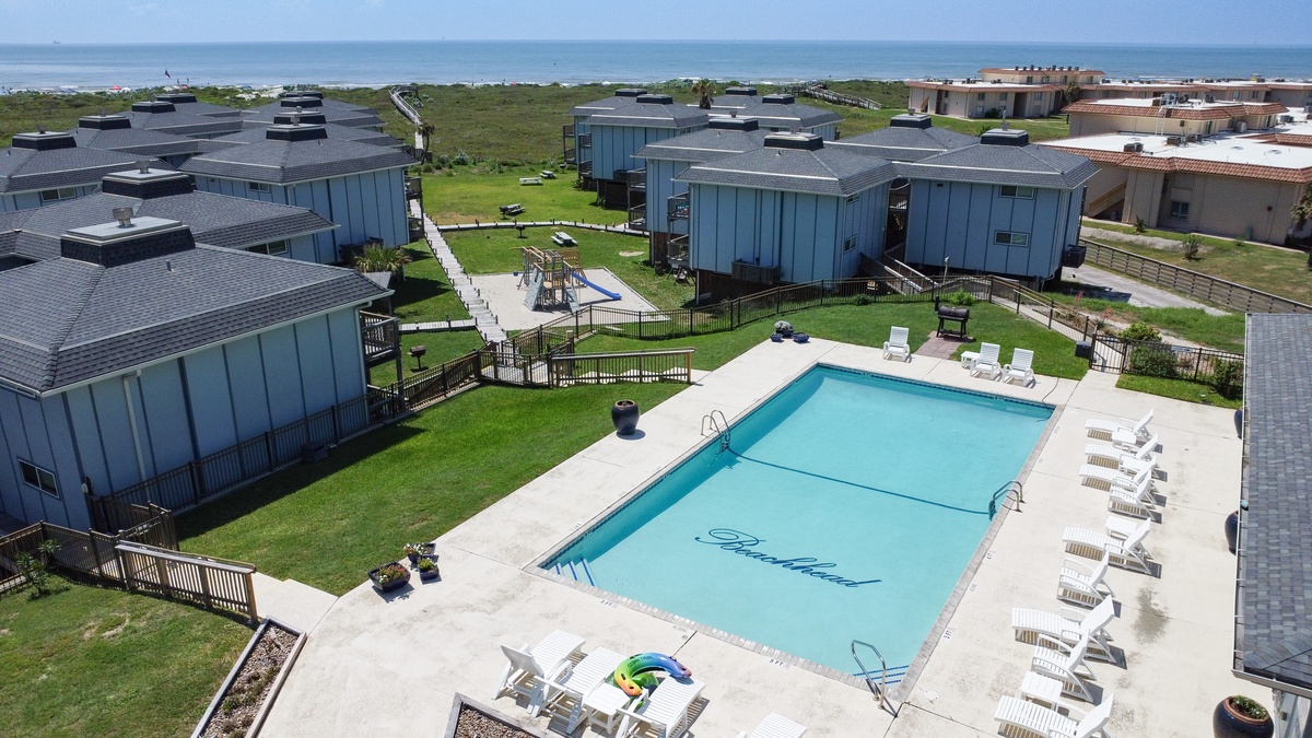 Modern beach resort with swimming pool surrounded by vacation homes near the ocean.