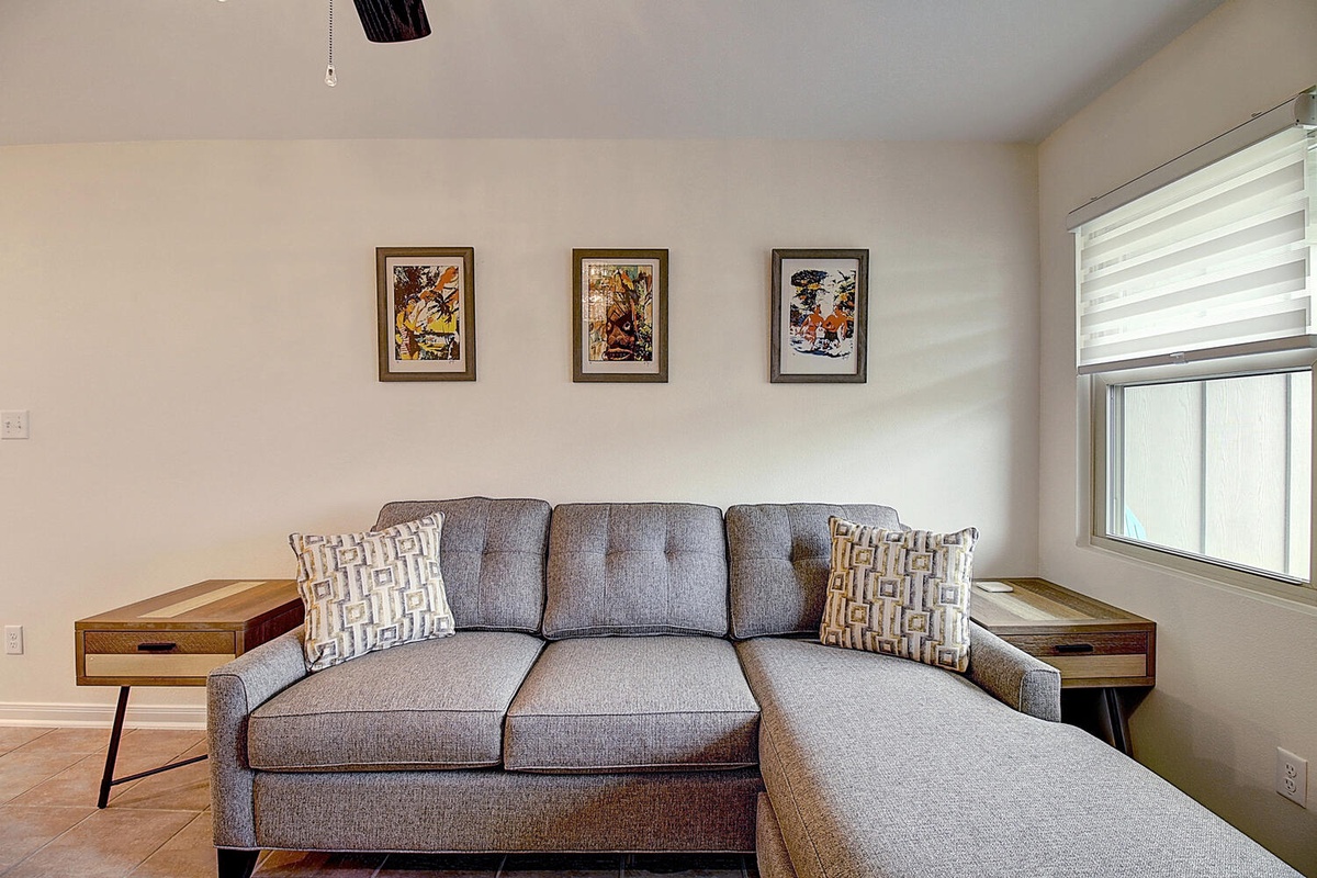 Sink into your stylish gray sectional and unwind in this bright, modern living space with curated artwork and warm wood accents.