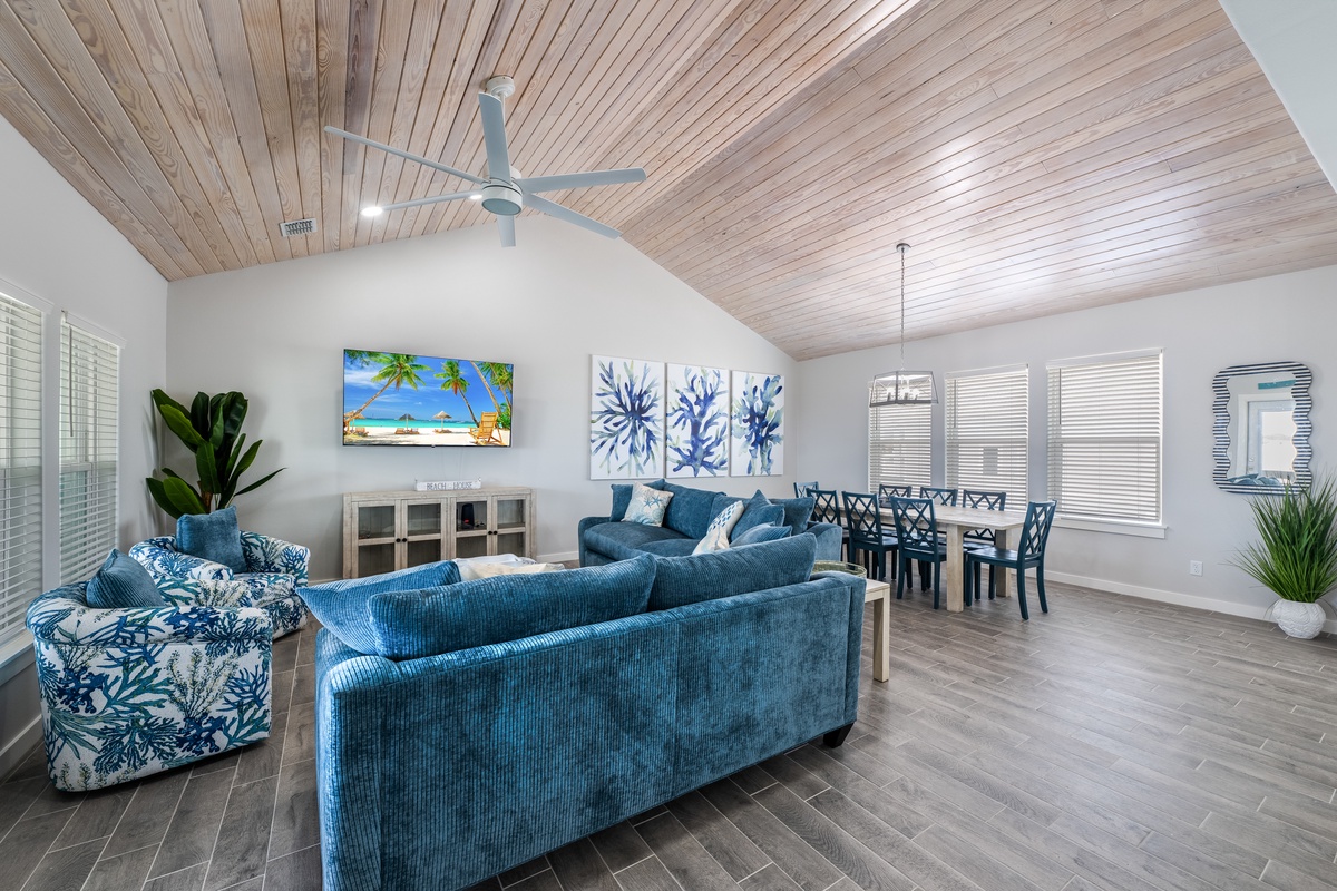 Relax in your bright coastal haven featuring plush blue furniture, warm wood ceilings, and tropical touches throughout.