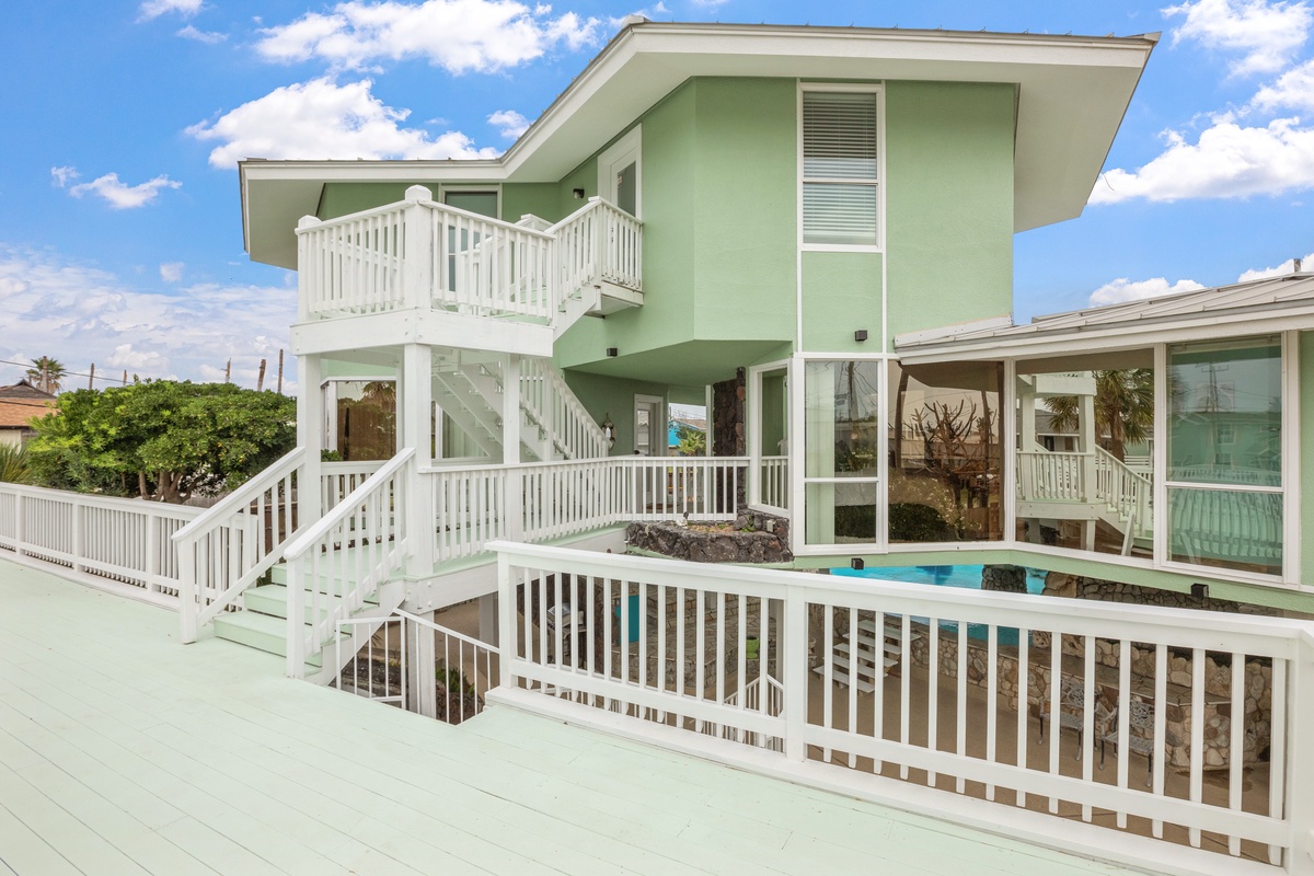 Bright coastal property featuring multi-level deck access, private pool, and modern design with tropical surroundings.
