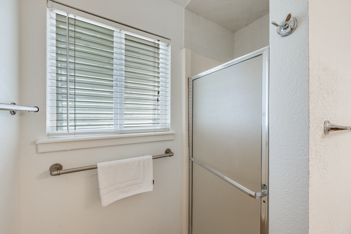Step into your bright, clean bathroom featuring a spacious walk-in shower and fresh towels ready for your comfort.