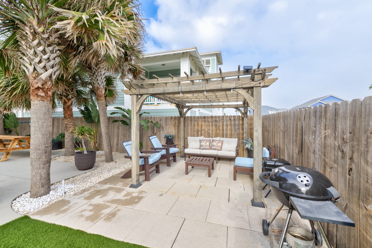 Relax in your private tropical oasis with comfortable patio seating and BBQ grill, perfect for outdoor dining under swaying palms.