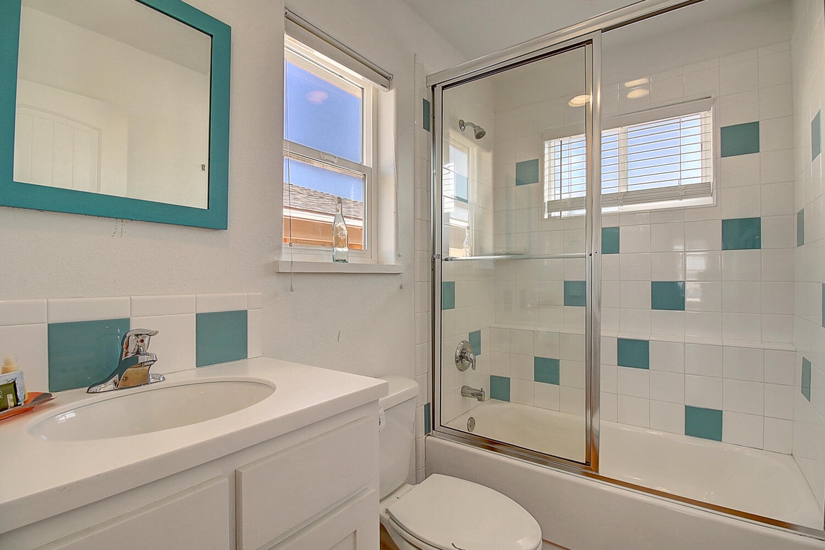 Refresh in your cheerful private bathroom featuring fun teal tile accents, natural light, and modern tub-shower combo.