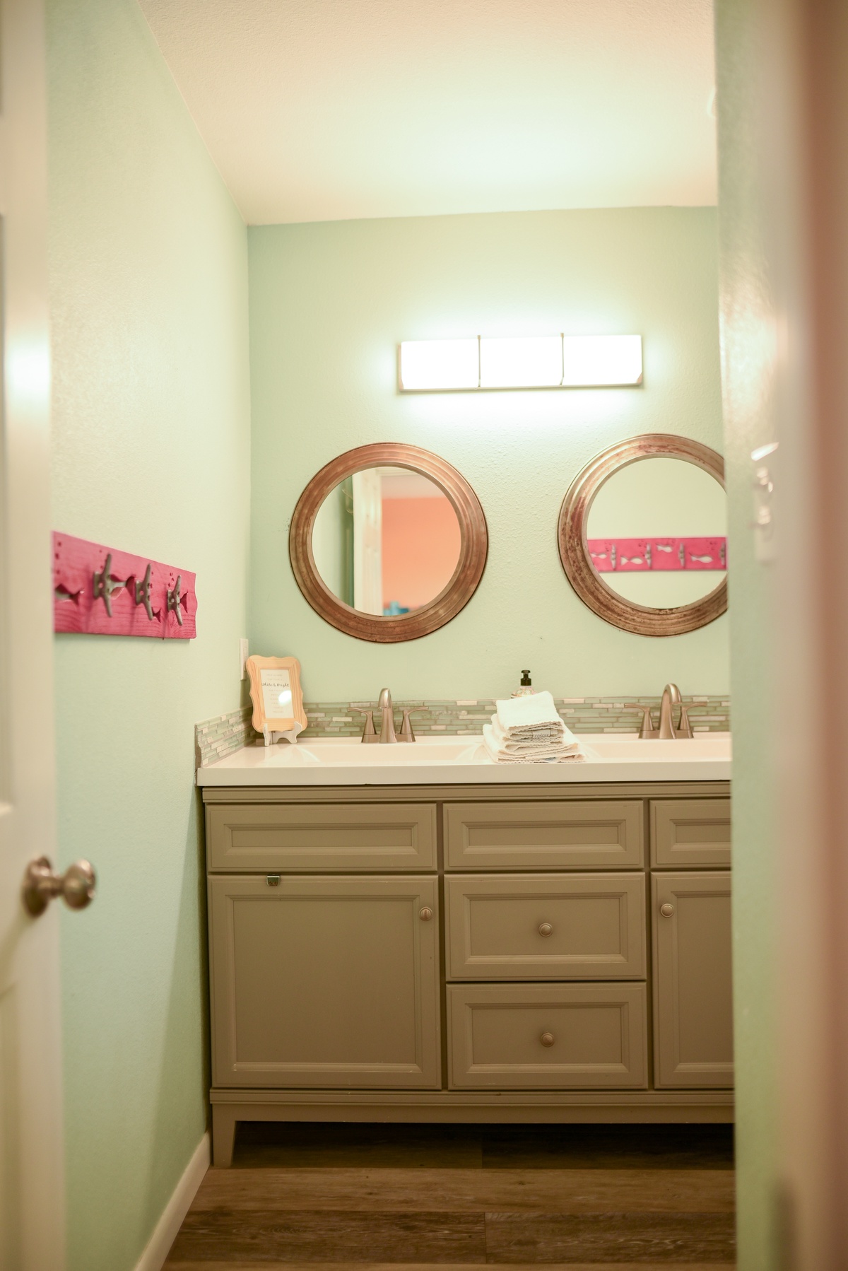Your bathroom features dual vanities with elegant round mirrors and soothing mint walls, creating a refreshing morning routine space.
