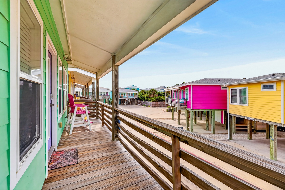 This coastal vacation rental community features vibrant, colorful cottages on stilts surrounding a shared courtyard—a cheerful beach getaway where relaxation meets playful seaside charm.