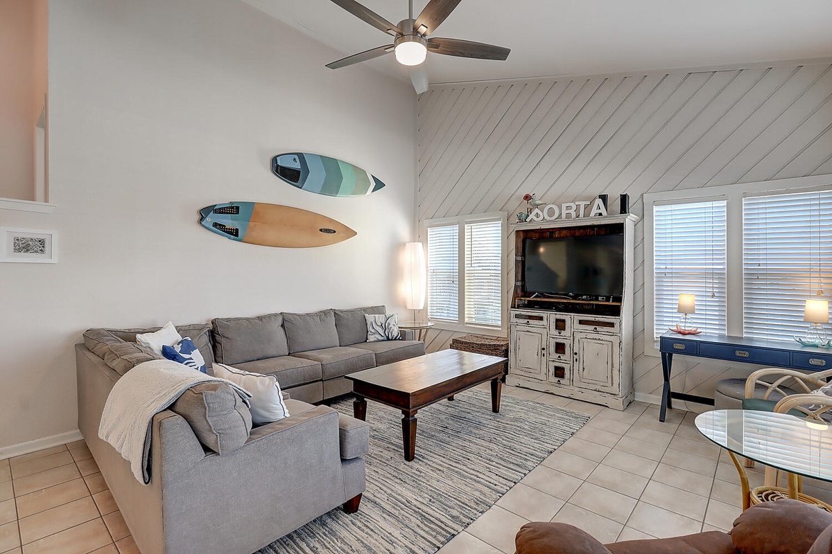 Unwind in your coastal-inspired living room with plush sectional seating and surfboard art that sets the beach vacation mood.