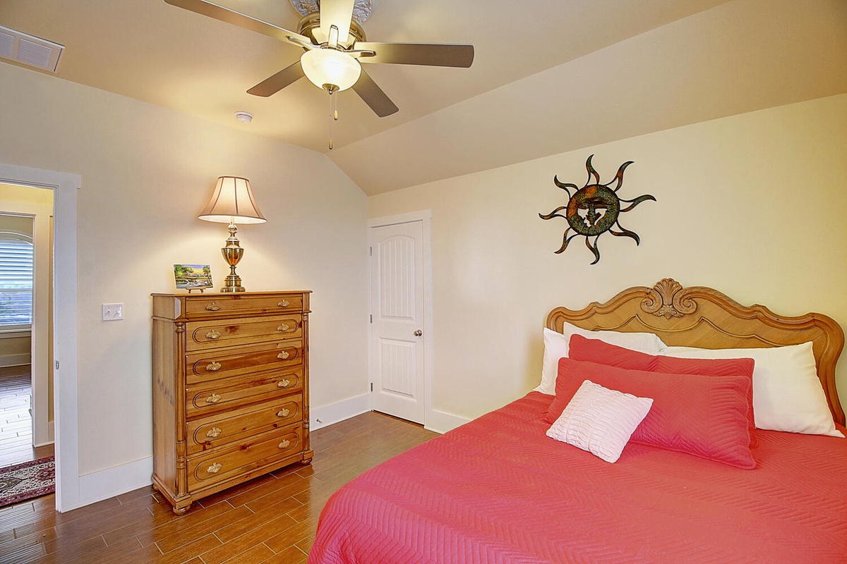 Your bright bedroom features a comfortable bed, charming vintage dresser, and gentle ceiling fan to keep you cool during restful nights.