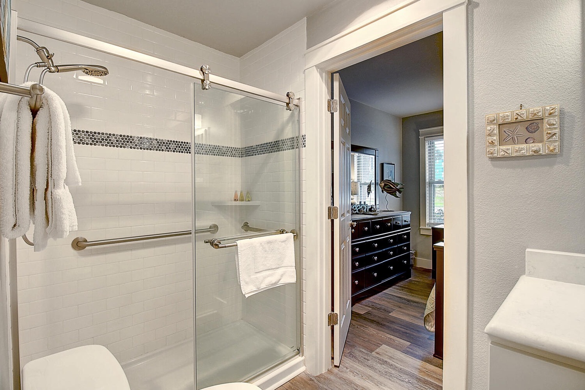 Step into your private bathroom oasis, featuring a spacious glass shower with rainfall head and fluffy towels waiting for you.