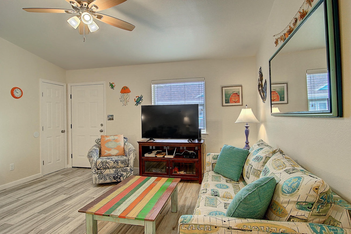 Unwind in your bright coastal living space with comfy seating, flat-screen TV, and cheerful beach-themed decor.
