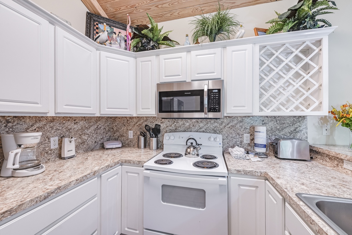 Your fully equipped kitchen awaits with granite countertops, modern appliances, and fresh plants creating a welcoming space for meal prep.