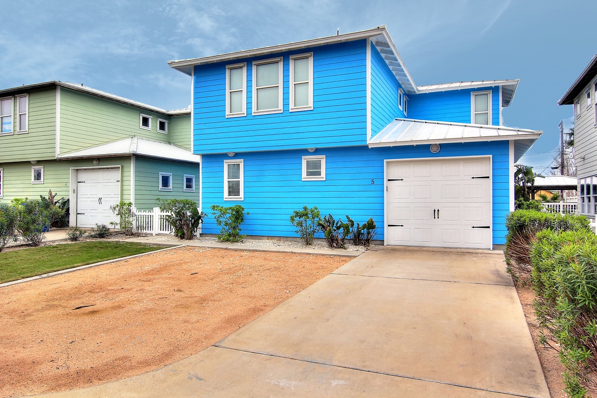 Vibrant blue coastal home with garage parking in a charming neighborhood setting.