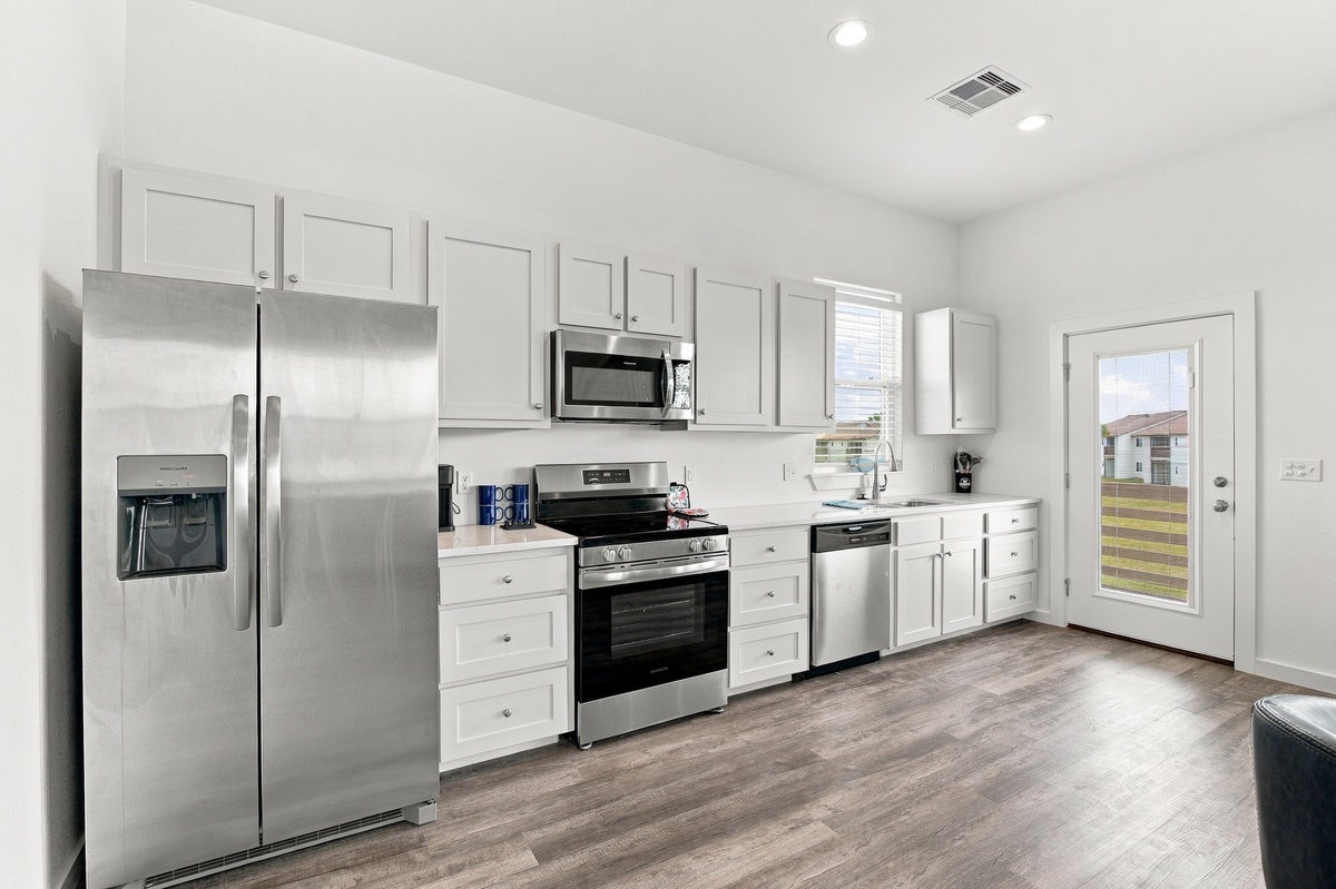 Fully equipped kitchen with stainless appliances, generous counter space, and crisp white cabinetry—everything you need to whip up meals or brew morning coffee.