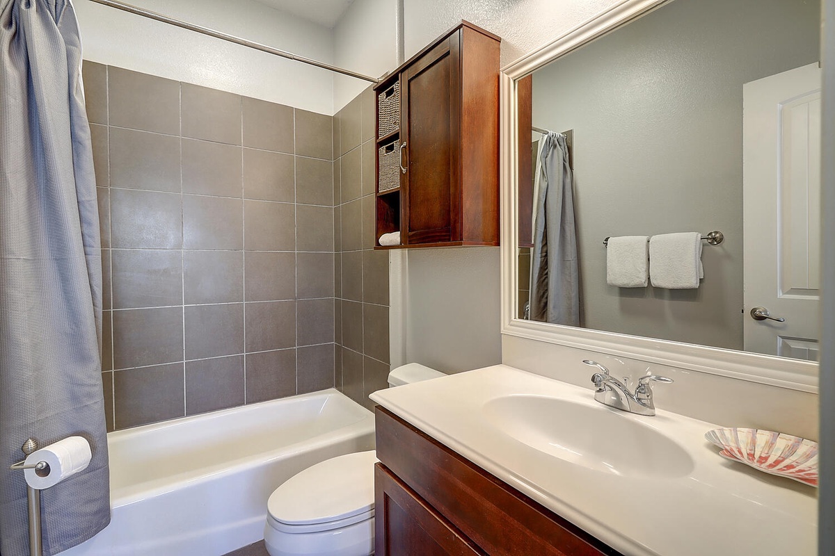 Unwind in your private bathroom with modern tiled shower, rich wood vanity, and thoughtful storage for all your essentials.