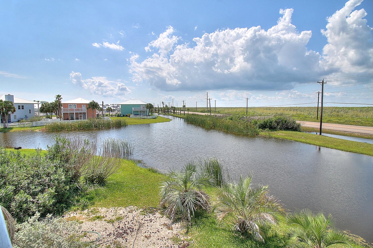 Peaceful waterfront canal community with charming homes and natural marshland surroundings under dramatic coastal skies.
