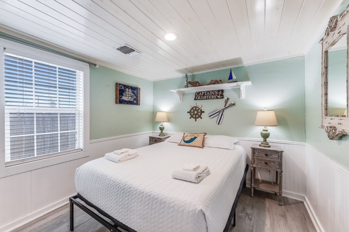 Your nautical-themed bedroom features crisp linens and coastal charm with ship's wheel decor and soothing sea-green walls.