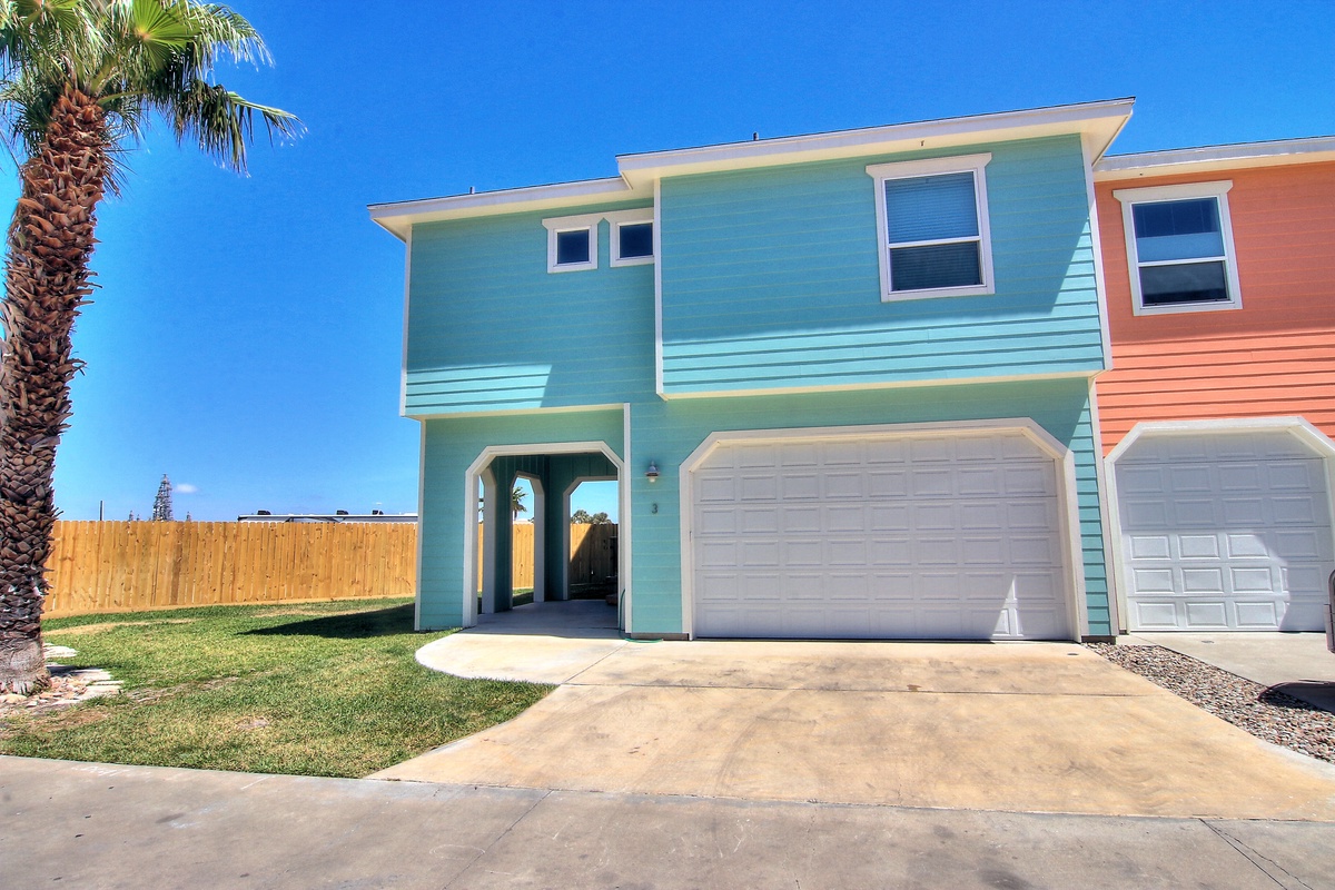Bright coastal-style duplex with tropical palm trees and convenient garage parking in a sunny residential neighborhood.