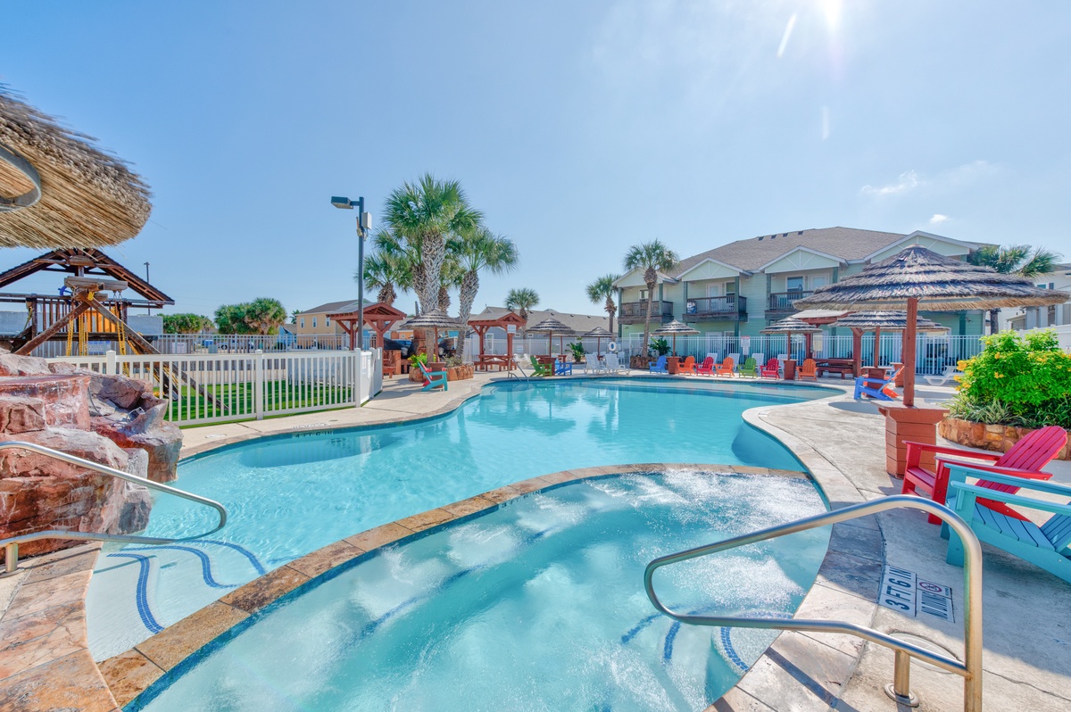 Dive into paradise with this sparkling pool and hot tub surrounded by tropical palms and colorful lounge chairs.