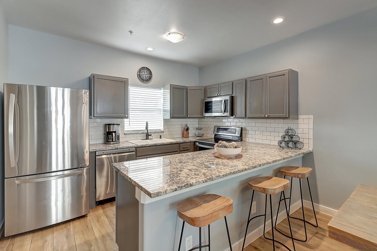 Your fully equipped kitchen features granite countertops, stainless steel appliances, and a breakfast bar perfect for morning coffee or casual dining.