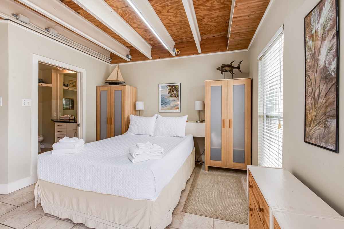 Unwind in your coastal bedroom with exposed wood beams, nautical decor, and crisp white linens creating the perfect seaside retreat.