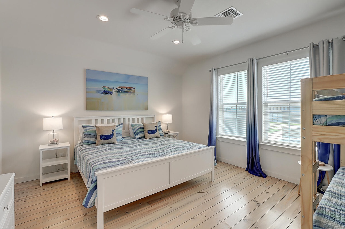 You'll love this bright coastal bedroom with ocean-themed artwork, comfy beds, and gentle ceiling fan breezes.