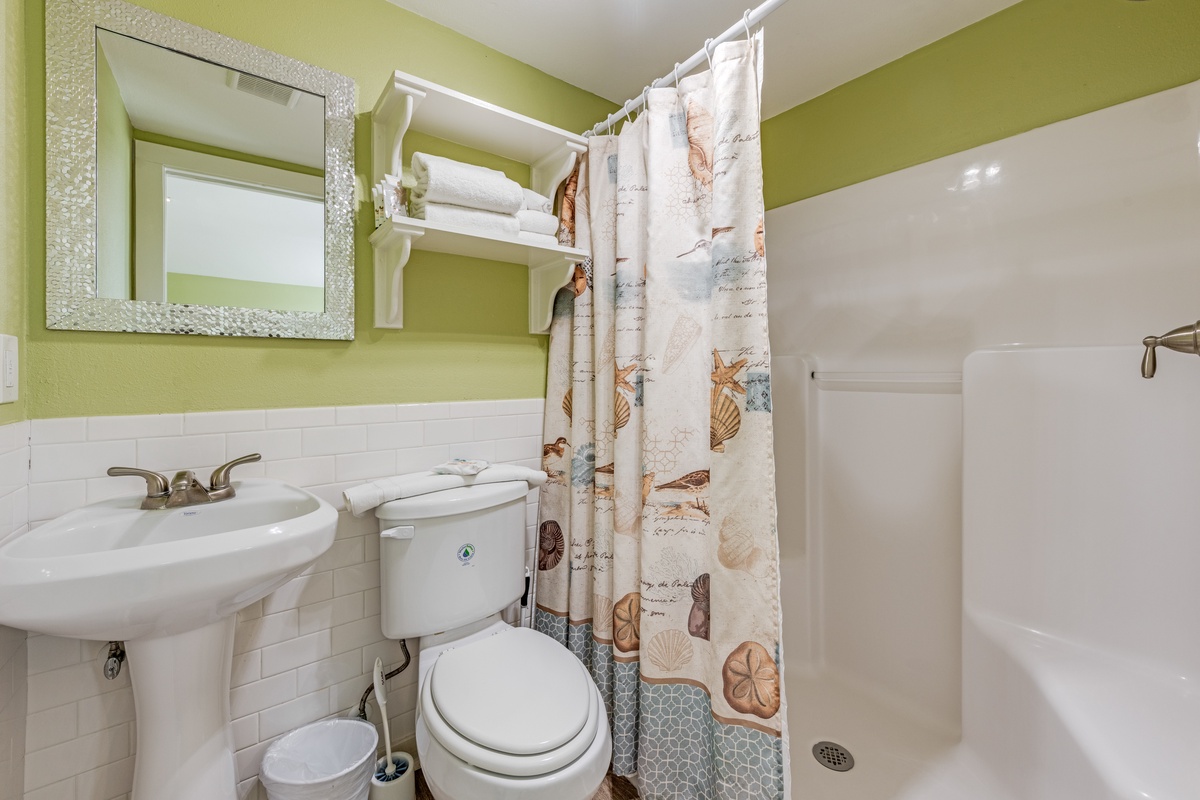 Step into your cheerfully bright bathroom featuring a walk-in shower, fresh towels, and coastal-themed touches that make getting ready feel like vacation.