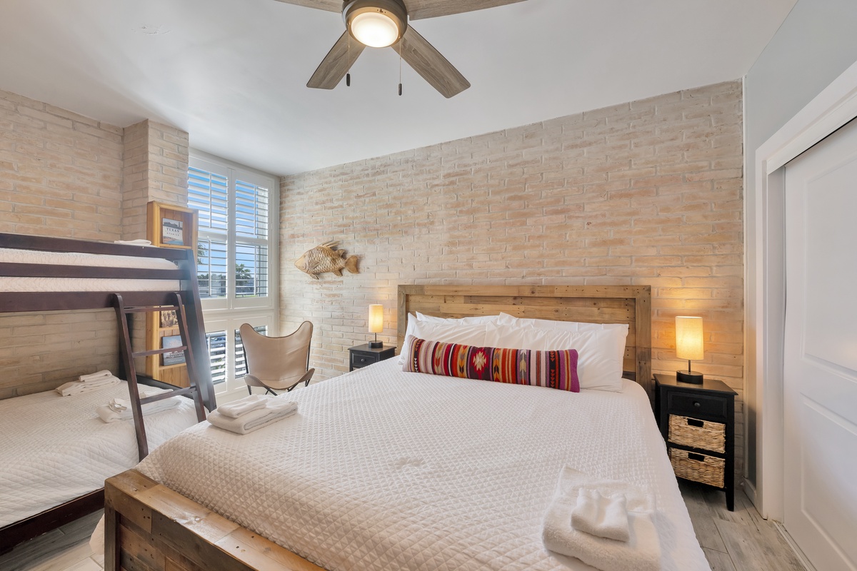 Drift off in your cozy bedroom featuring exposed brick, warm wooden accents, and soft lighting that creates the perfect atmosphere for rest.