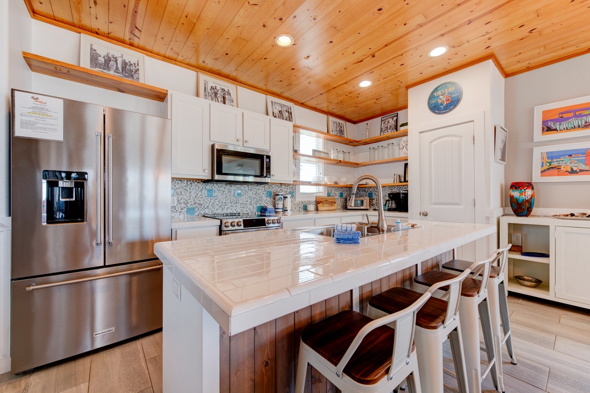 Your chef-worthy kitchen awaits with gleaming countertops, stainless appliances, and warm wood ceiling—perfect for creating memorable meals together.