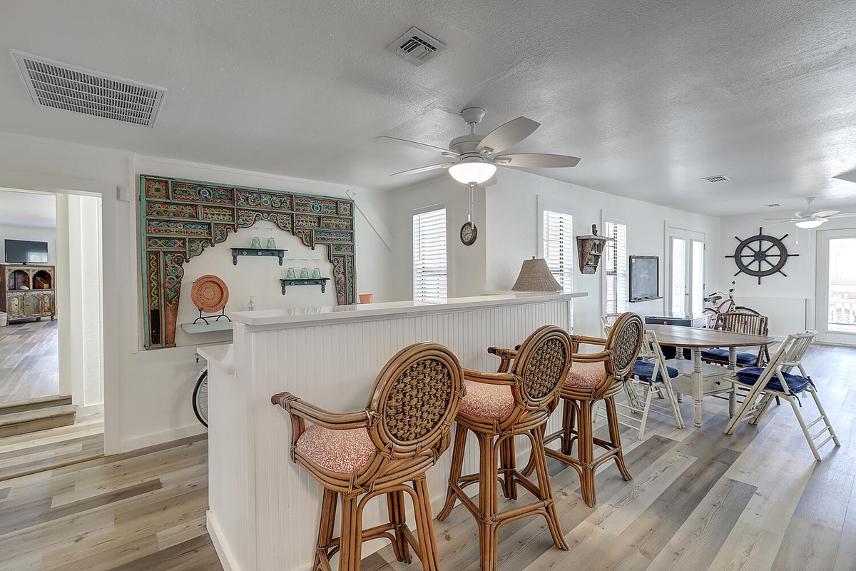 Your coastal kitchen features elegant wicker bar stools and charming nautical decor, perfect for morning coffee or evening conversations with family.